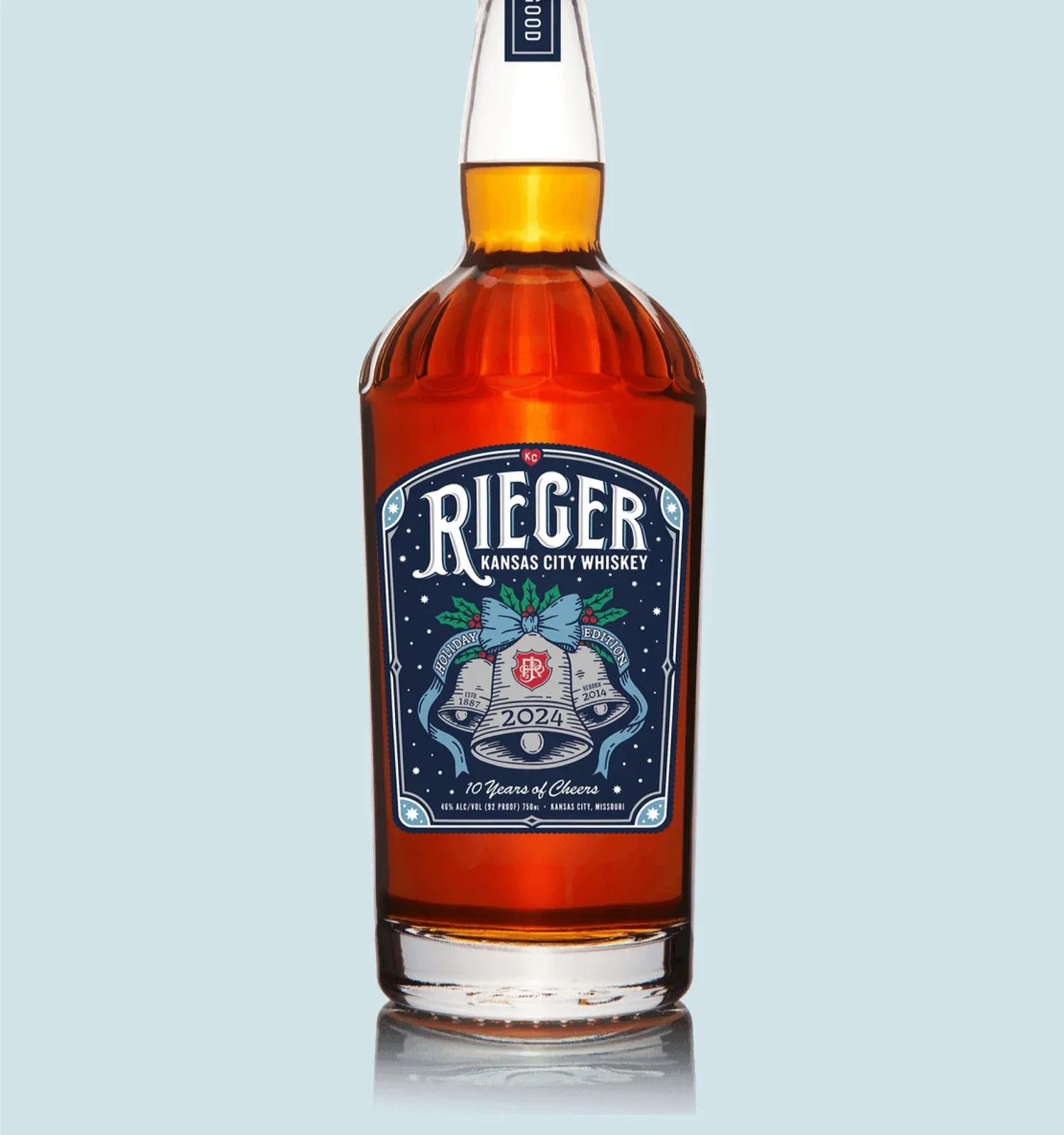 J. Rieger 2024 Holiday Whiskey bottle mockup on neutral background, displaying the complete label design with silver foil bells and nighttime composition